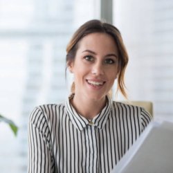 lauramartinez Portrait of smiling millennial businesswoman holding documents looking at camera, headshot of happy woman worker or female ceo posing with paperwork making picture at corporate photoshoot.